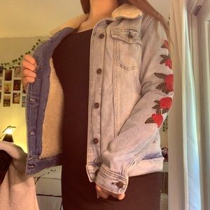 jean jacket with floral pattern on the sleeves.